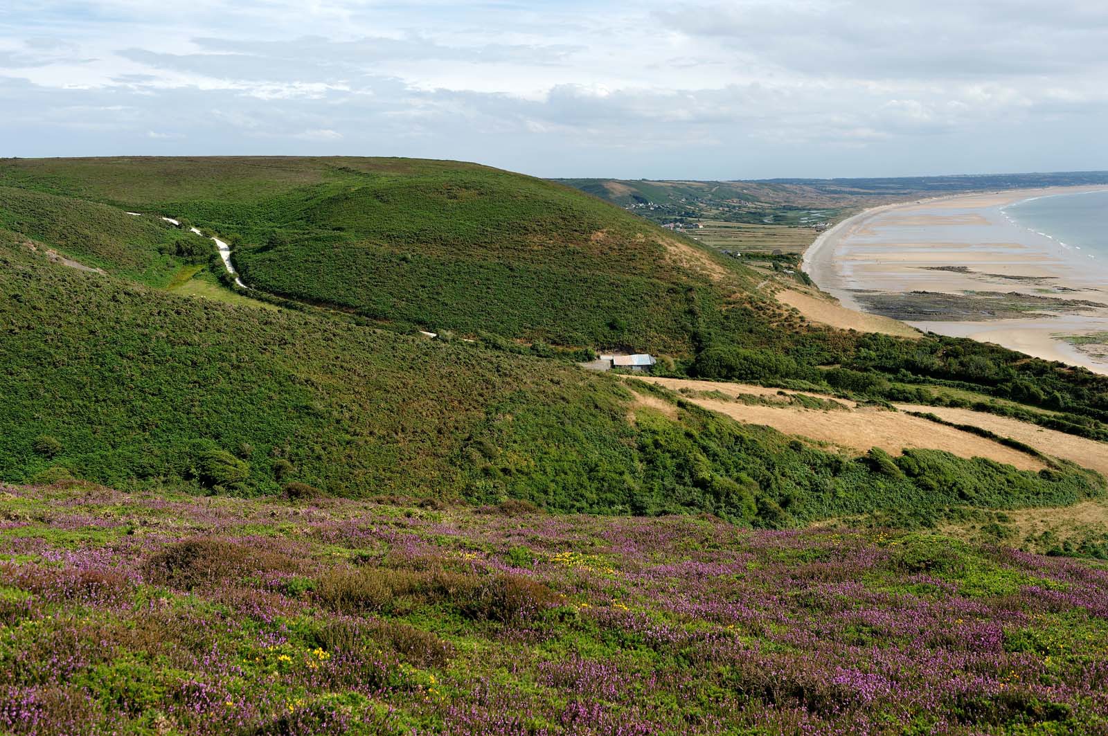 Le village de Vauville fait partie des sites classés de la Hague, Cap Cotentin. Les Pierres Pouquelées, galerie néolithique, sont un témoignage de l'Antiquité.La mare de Vauville est une réserve naturelle. Créée en 1976 c'est l'une des 135 réserves naturelles de France. Géré par le Groupe Ornithologique Normand depuis 1983, c'est un marais d'eau douce protégé de la mer par un étroit cordon dunaire. La mare de Vauville fait 62 ha, il y a plus de 150 espèces d'oiseaux ainsi que de 350 plantes et 16 espèces de batraciens.Un édifice autrefois religieux domine le village. C'est le prieuré de Vauville construit dans les landes, sur le haut d'une colline.Créé par Eric et Nicole Pellerin en 1947, l'exceptionnel jardin botanique du château de Vauville occupe plus de 40 000 m2. Abritant plus de 1000 espèces de l'hémisphère austral, le jardin entoure le château de Vauville dans une ambiance subtropicale tout à fait surprenante.