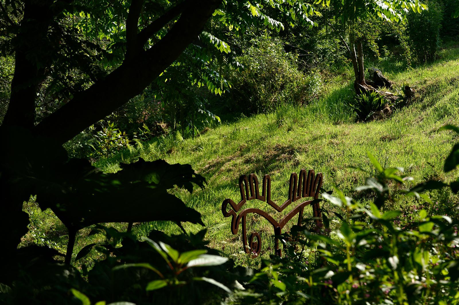 En hommage au poète, ses amis dont Gérard Fusberti, propriétaire du terrain et gardien du temple, décident de créer un jardin où chacun plantera son arbre ou laissera une de ses créations. Montand, Reggiani, Greco ou Mouloudji plantèrent chacun leur double végétal lors de la célébration du dixième anniversaire de la mort de Prévert, un eucalyptus aujourd'hui haut d'au moins 20 mètres pour Mouloudji.Se balader dans ce jardin, c'est pénétrer dans l'univers du poète. Au milieu des arbres d'ornement, des bambous peints de rouge vif, des arbres fruitiers, des camélias, des azalées, des gunneras (que Prévert adorait) et des hortensias, des œuvres d'art se révèlent ça et là, tantôt un portrait, tantôt une sculpture ou une installation. Des arbres peints prennent vie, une main rouge semblant sortir de leur entrailles, le ruisseau qui coule en cascade murmure une douce poésie, que l'on retrouve en quelques phrases inscrites sur des plaques qui surgissent au milieu de cette jungle organisée. (Saint-Germain-des-Vaux Manche)